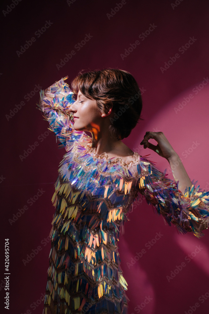 Teen model posing in dramatic light wearing shiny dress Teen model posing in dramatic light wearing shiny dress