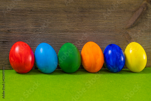 Easter eggs on green table against wooden background