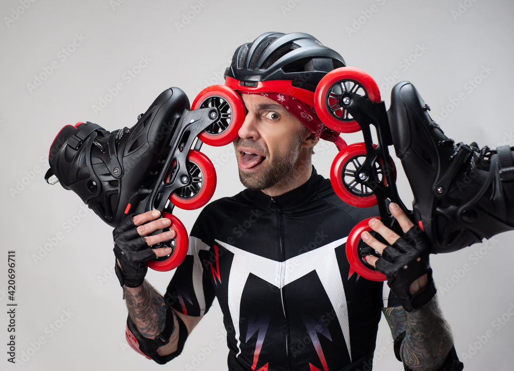 a man in sports clothes and a helmet with roller skates in his hands on a white background