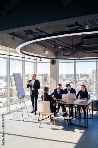 The boss stands near the board with graphs, demonstrates statistics, various personnel attending the training, introduces the new products of the company, reports on the results of work for partners.