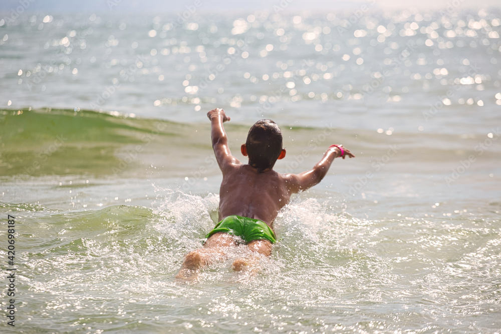 Fototapeta premium child swims in the sea waves on the beach