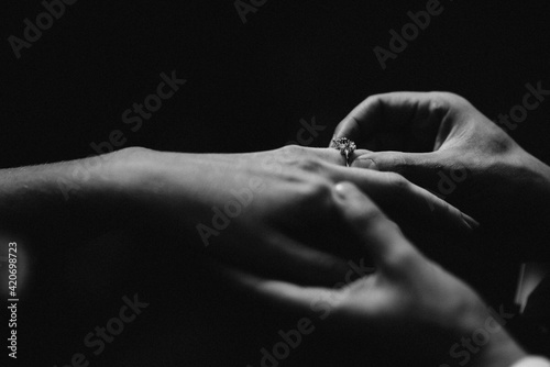 monochrome image of putting ring on woman