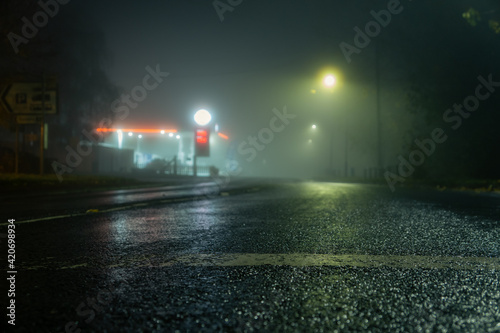 A low angle shot of a road and petrol station street on a foggy night
