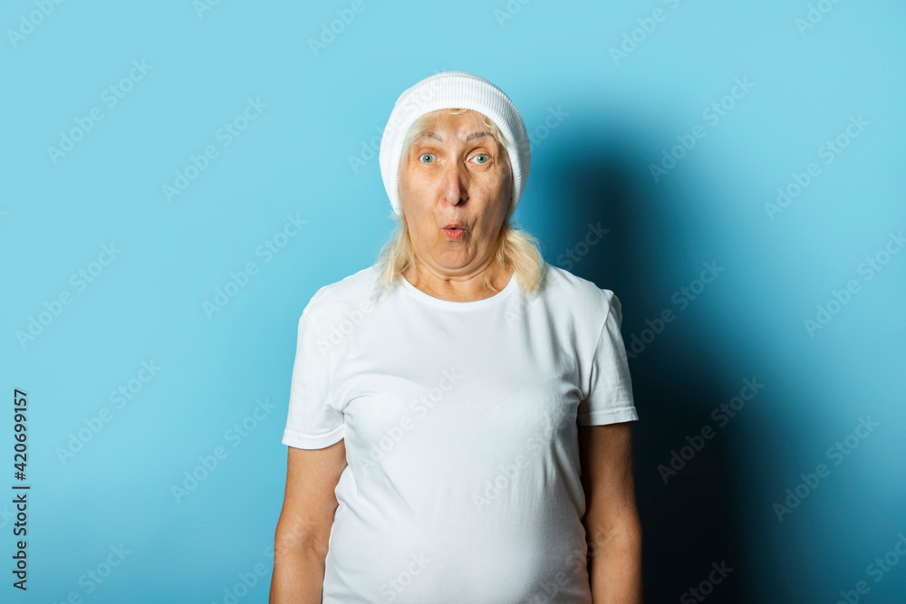 Funny old woman in a hat on a blue background. Concept cool stylish grandmother, modern style Funny old woman in a hat on a blue background. Concept cool stylish grandmother, modern style