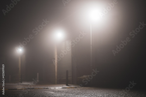 The doors of a warehouse lit up by security lights on a foggy night photo