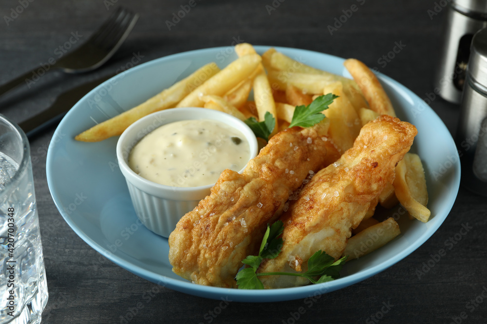 Concept of tasty eating with fried fish and chips on dark textured table