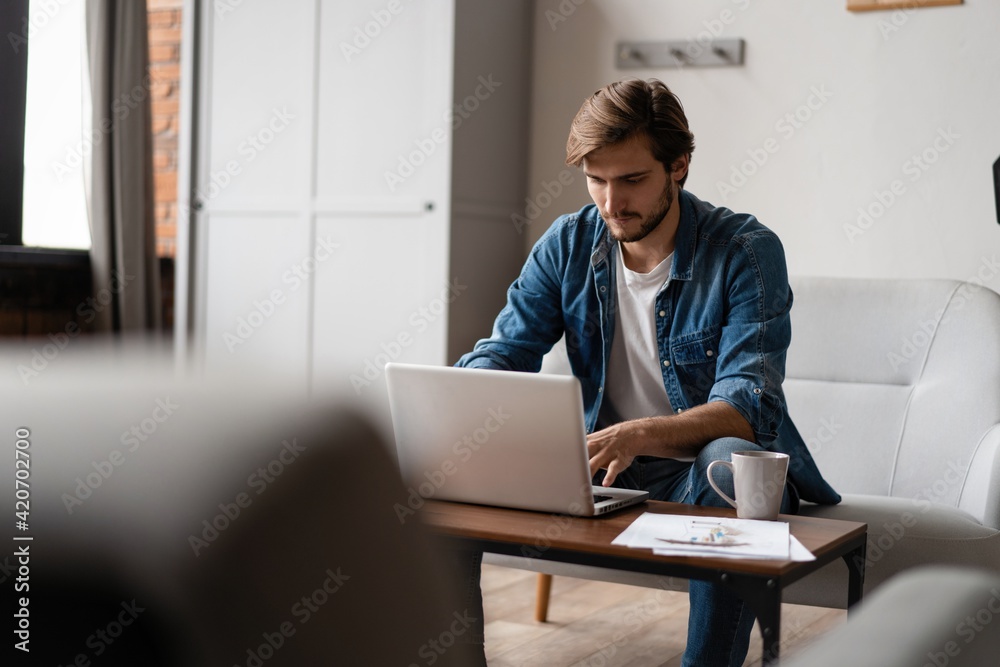 Entrepreneur working with a laptop and holding a document in a little office or home Entrepreneur working with a laptop and holding a document in a little office or home