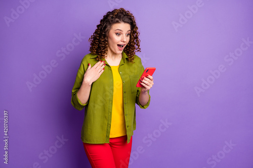 Photo of young happy excited amazed woman hold hand chest see unexpected news in phone isolated on purple color background