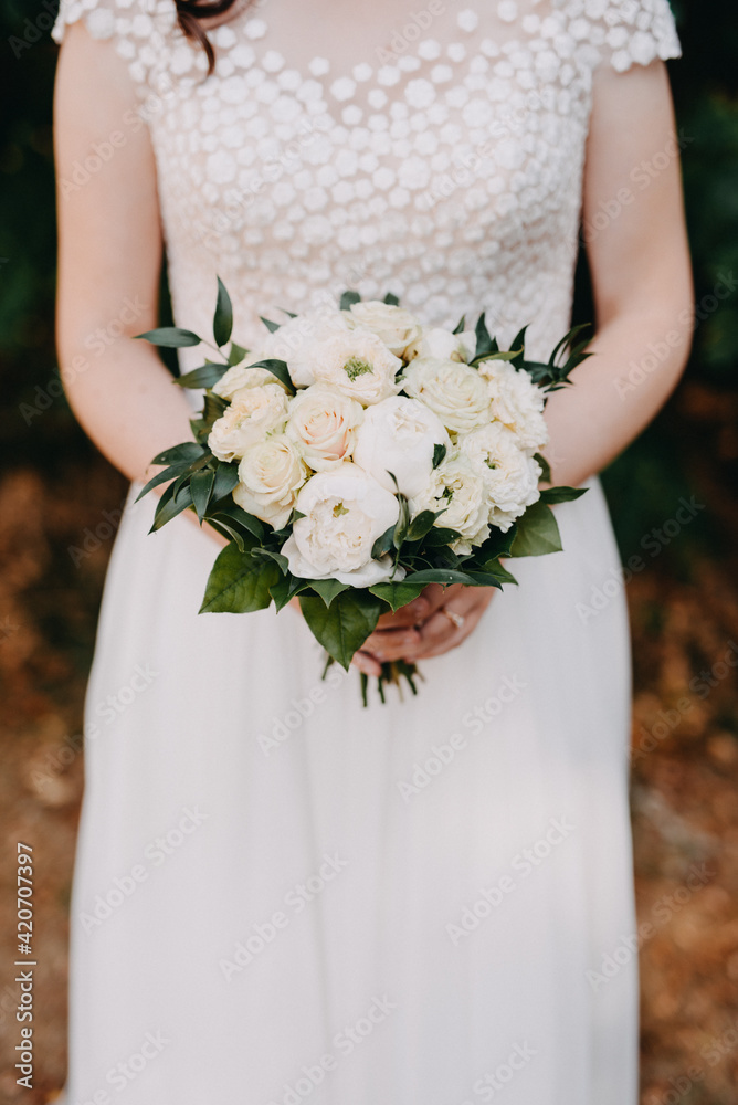 Bride with white wedding dress holding a simple minimalistic wedding bouquet in white Bride with white wedding dress holding a simple minimalistic wedding bouquet in white