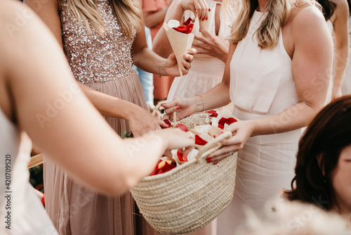 bridesmaids holding a rotan bag with flower confetti for wedding guests photo