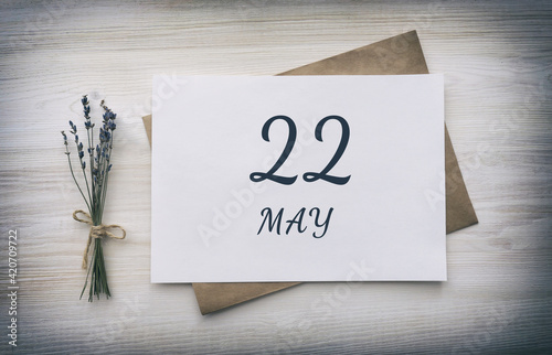 may 22. 22th day of the month, calendar date. White blank of paper with a brown envelope, dry bouquet of lavender flowers on a wooden background. Spring month, day of the year concept