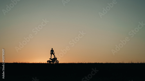 Silhouette Of A Man Standing On The Motorcycle photo