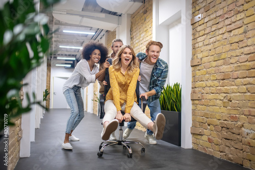 Foto Group of young people riding the chair in the office corridor after a nice day