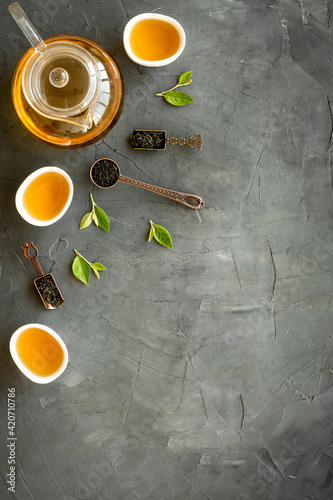 Tea green leaves with teapot and cups, top view. Tea ceremony concept.