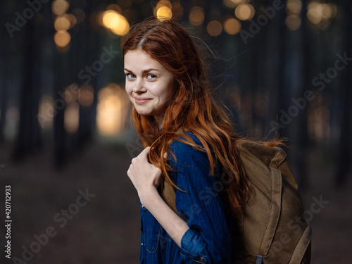 Happy woman travels among pine trees in nature in the forest