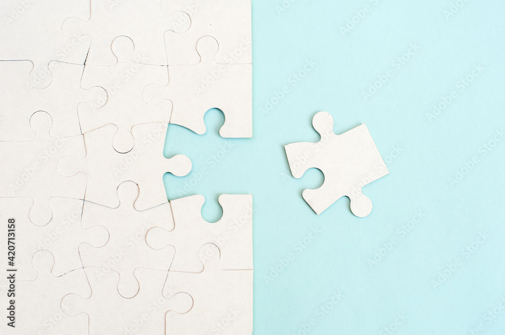 White puzzle background with missing piece on blue background. Top view White puzzle background with missing piece on blue background. Top view