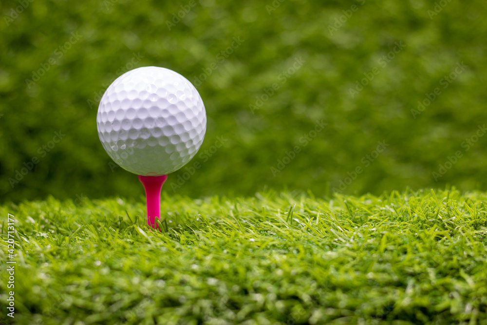 Golf ball is on tee ready to tee off on green grass background Golf ball is on tee ready to tee off on green grass background