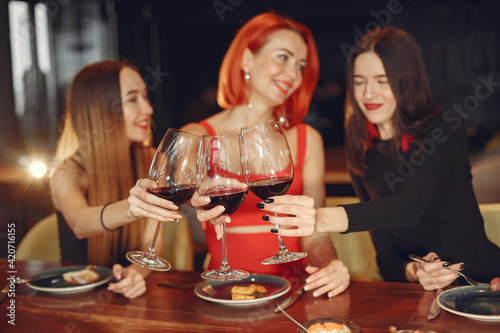 Friends talking and having fun at dinner party. Elegantly dressed women of people having a dinner.