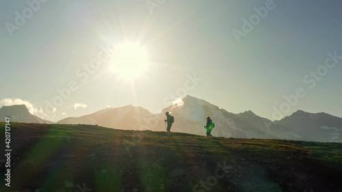 Silhouettes of two young hikers (a couple) walking on a mountain ridge in Austria in summer