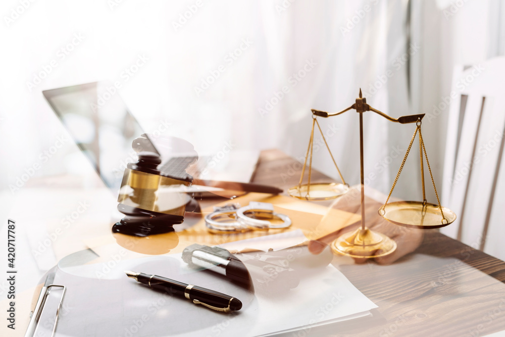 Business and lawyers discussing contract papers with brass scale on desk in office. Law, legal services, advice, justice and law concept picture with film grain effect Business and lawyers discussing contract papers with brass scale on desk in office. Law, legal services, advice, justice and law concept picture with film grain effect