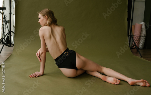 Back of blonde girl in underwear sits on the lime background photo