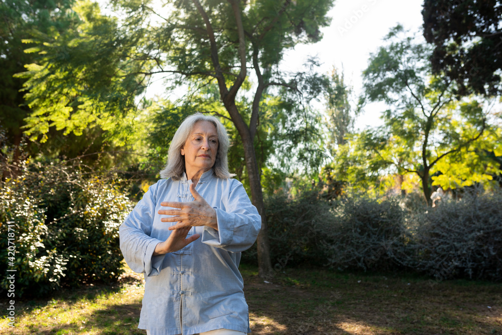 grey hair mature woman practicing tai chi in the city park