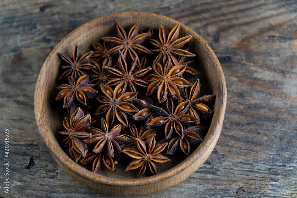 Anise star. Stars in a wooden plate on a brown background. Fragrant seasoning. The bowl is on the rustic table