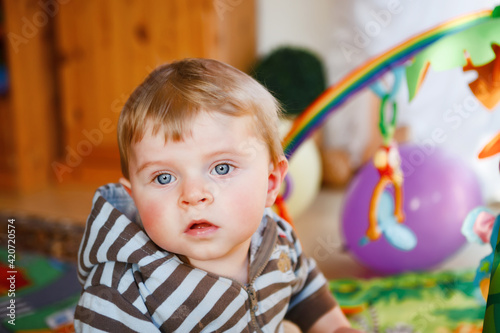 Portrait of little child, cute adorable baby boy playing with colorful toys. Happy, curious kid at home, indoors.