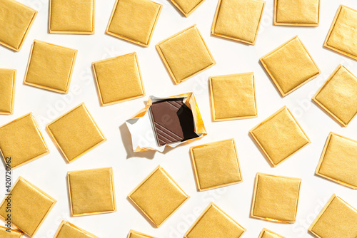 Unwrapped chocolate near pieces in golden wrappings photo