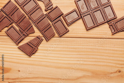 broken bar of chocolate on wooden background texture sweets