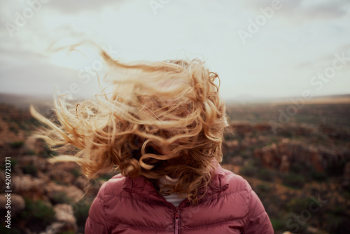 Closeup of young woman face covered with flying hair in windy day standing at mountain