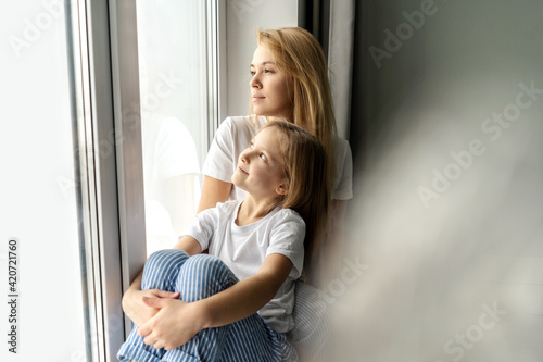 Mom with little girl near window.
