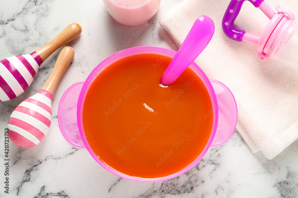 Flat lay composition with bowl of healthy baby food on white marble table Flat lay composition with bowl of healthy baby food on white marble table