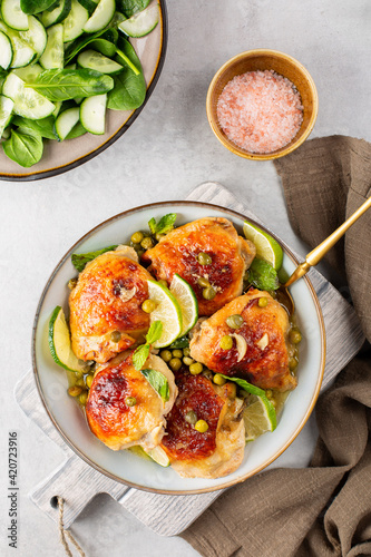 Chicken marinated with butter, honey and mustard and baked  with spring peas, capers, served with lime and fresh mint. Fresh salad. Top view, vertical image. photo