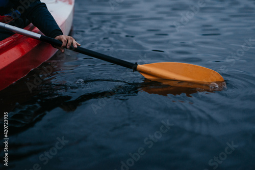 red canoe on a lake with orange yellow oar in the water