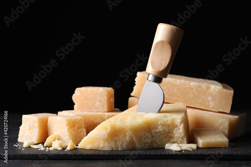 Parmesan cheese with slate plate and knife on table, closeup
