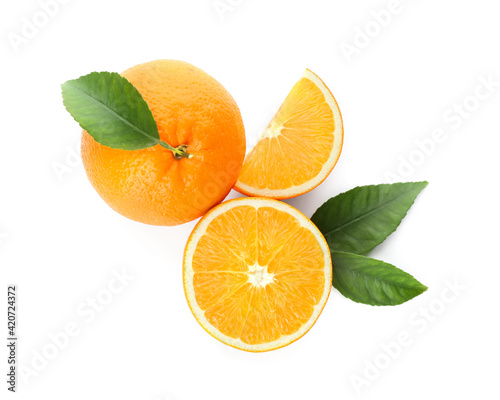 Cut and whole fresh ripe oranges with green leaves on white background  top view