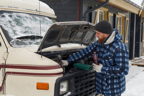 Bearded man changing antifreeze in van photo