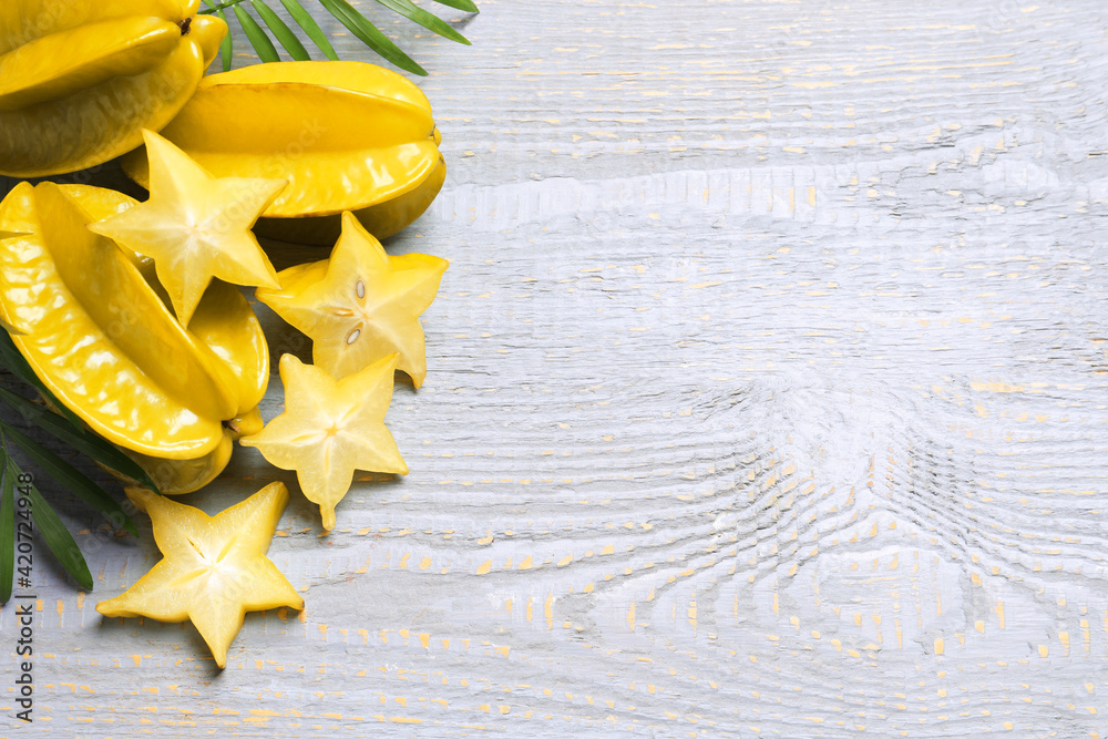 Delicious carambola fruits on light grey wooden table, flat lay. Space for text Delicious carambola fruits on light grey wooden table, flat lay. Space for text