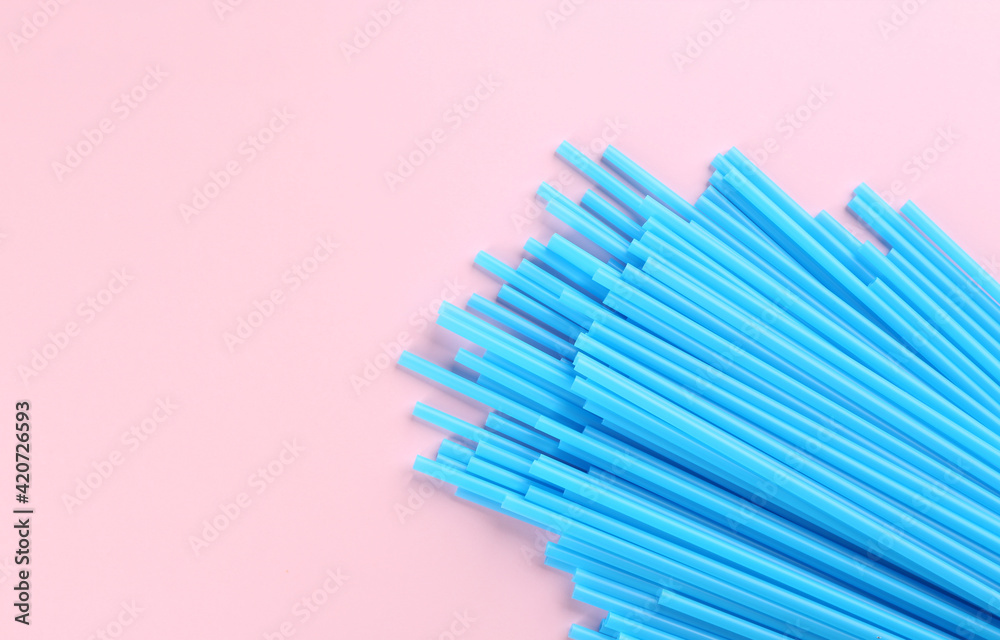 Heap of blue plastic drinking straws on pink background, flat lay. Space for text Heap of blue plastic drinking straws on pink background, flat lay. Space for text