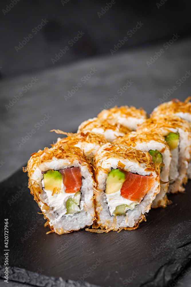 appetizing philadelphia sushi roll with tuna salmon avocado chips and cucumber on a black stone plate appetizing philadelphia sushi roll with tuna salmon avocado chips and cucumber on a black stone plate