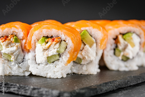 appetizing sushi roll philadelphia with avocado cheese eel cucumber and salmon on a black stone plate