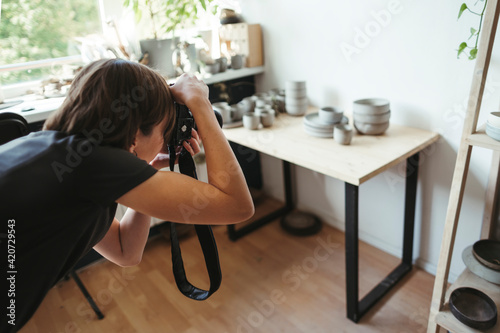 Female artisan photographs ceramic products. photo