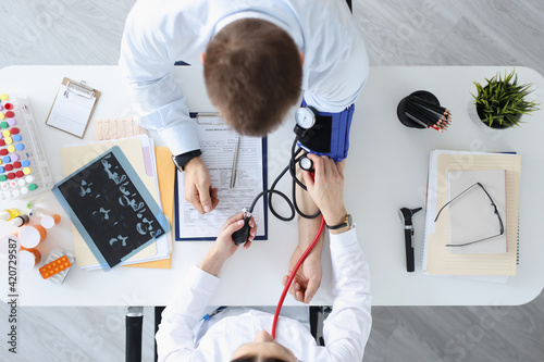 Doctor measuring pressure on patients shoulder top view photo