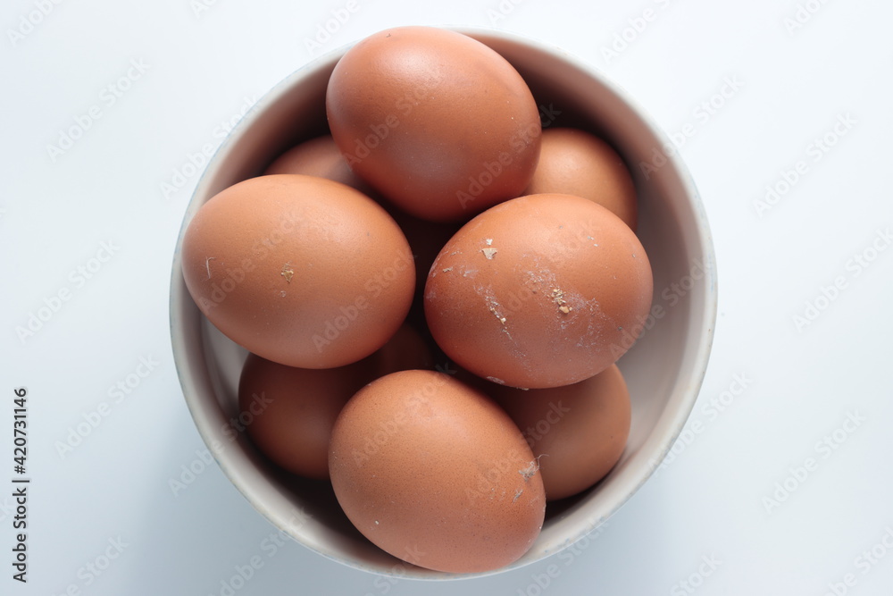 Top view of dirty unwashed brown chicken eggs in a white bowl isolated in white background Top view of dirty unwashed brown chicken eggs in a white bowl isolated in white background