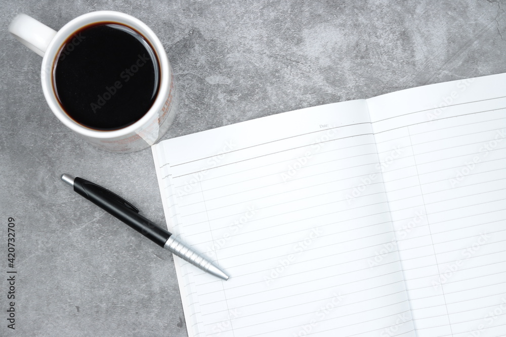 coffee, blank notebook and a pen on cement concrete surface floor. coffee, blank notebook and a pen on cement concrete surface floor.