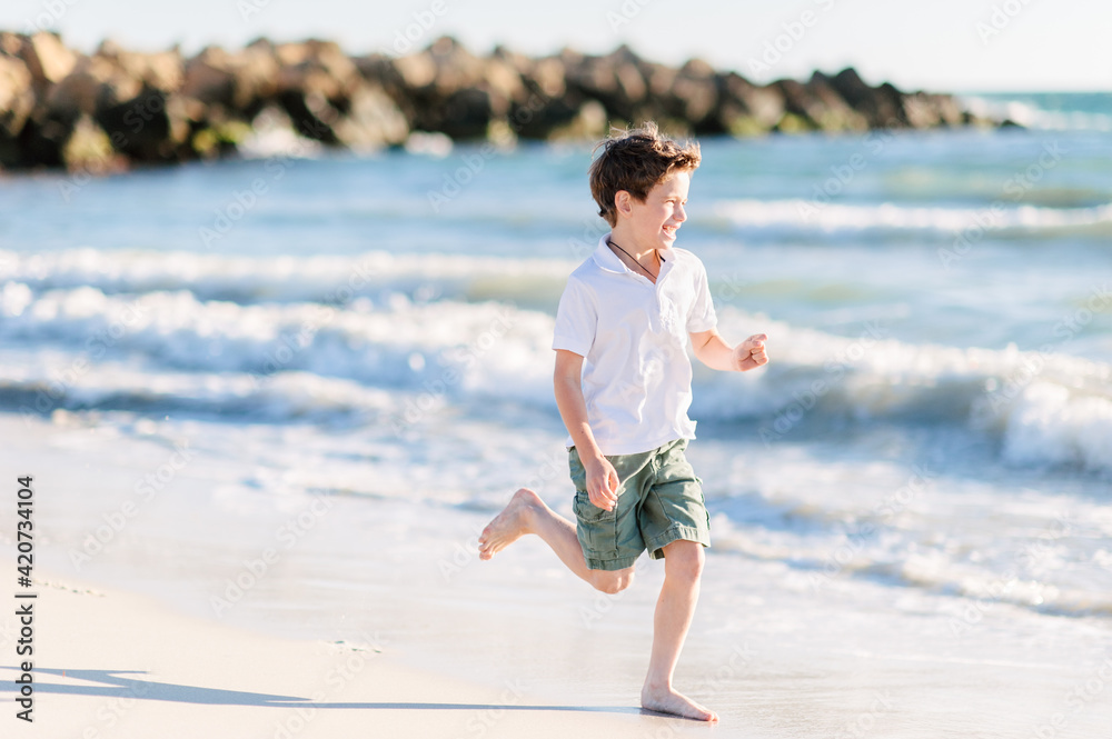 Boy running on sand by the water at the beach Boy running on sand by the water at the beach