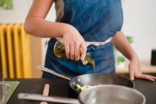 Crop woman cooking vegetables with oil