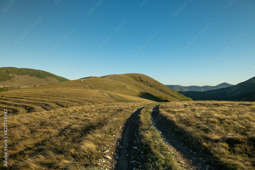 Landscape view of Caucasus hills with unusual geology pattern.  Landscape view of the foothills of the Caucasus. Path with tire tracks over the hills.