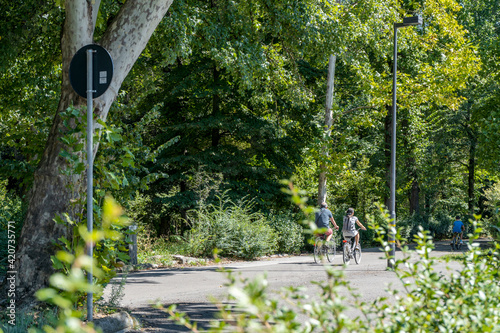 A trail for trekking and cycling in the woods of the Cascine monumental park with two cyclists, in Florence, Tuscany, Italy photo